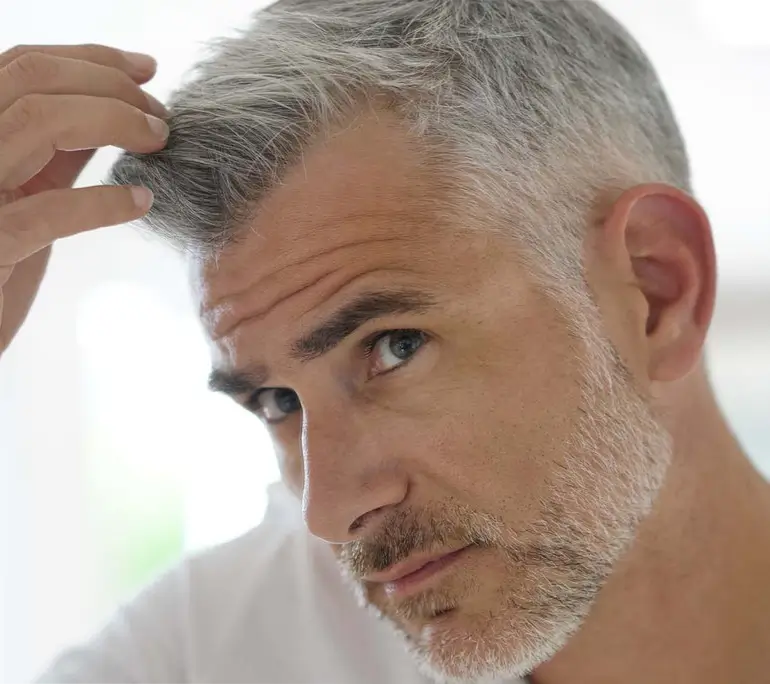 middle aged man using mirror while touching hair 1